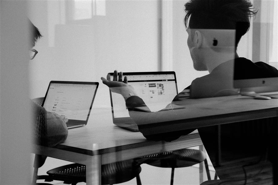 Consultants en réunion de travail avec ordinateurs portables, symbolisant l'accompagnement stratégique en TI.